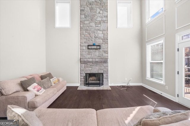 living room with dark hardwood / wood-style flooring, plenty of natural light, a fireplace, and a high ceiling