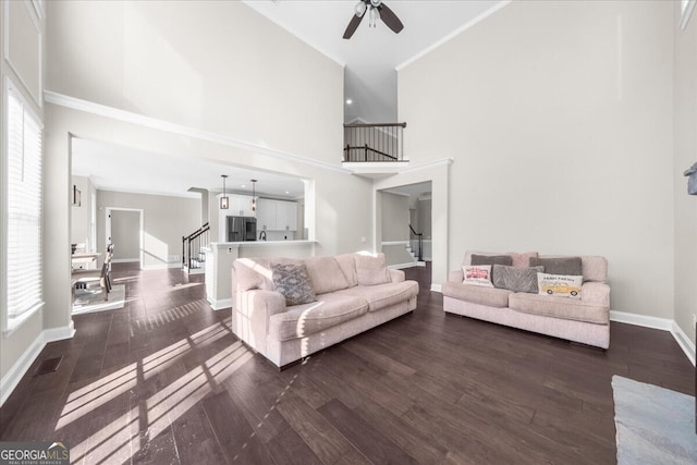 living room featuring ceiling fan, hardwood / wood-style floors, a towering ceiling, and crown molding