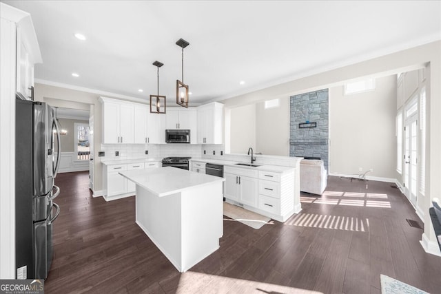 kitchen featuring appliances with stainless steel finishes, white cabinetry, a kitchen island, and sink