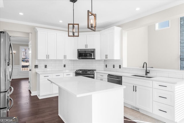 kitchen featuring pendant lighting, a center island, white cabinets, sink, and appliances with stainless steel finishes