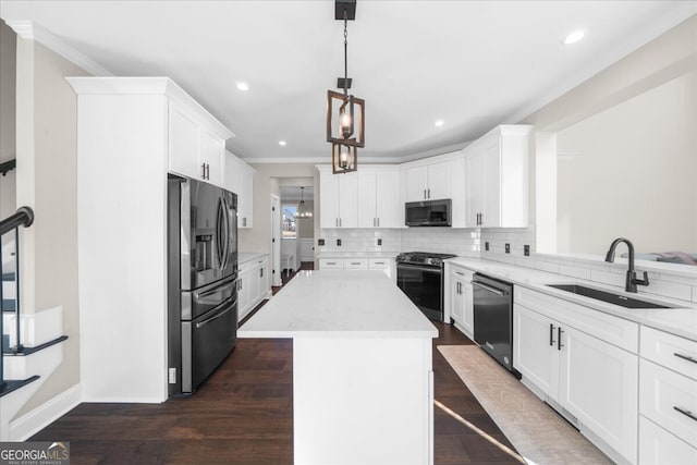 kitchen featuring appliances with stainless steel finishes, sink, decorative light fixtures, white cabinetry, and a kitchen island