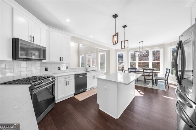 kitchen featuring pendant lighting, white cabinets, sink, light stone countertops, and stainless steel appliances