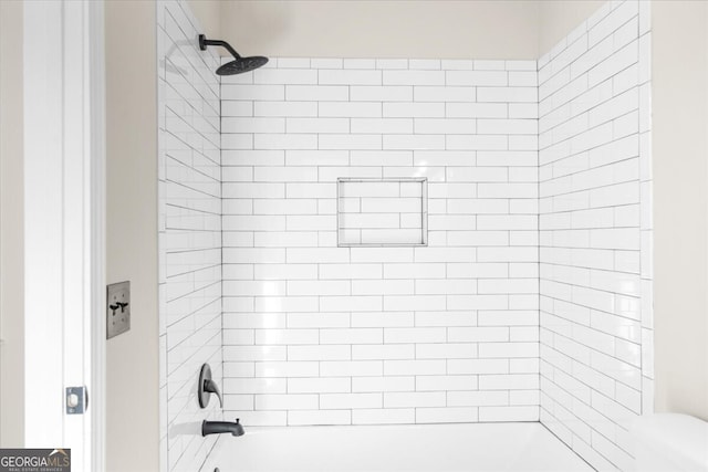 bathroom featuring toilet and tiled shower / bath