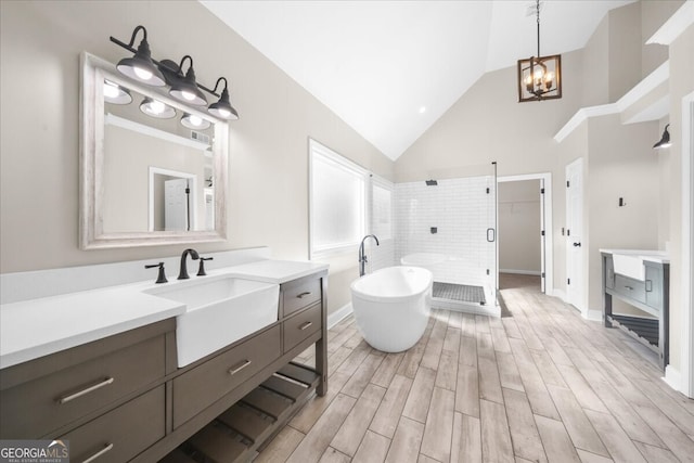 bathroom with separate shower and tub, vanity, high vaulted ceiling, and an inviting chandelier