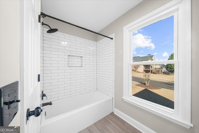 bathroom featuring wood-type flooring and tiled shower / bath