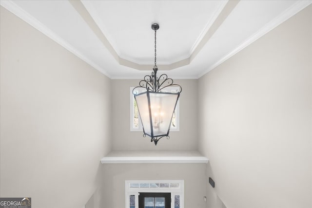 interior details with ornamental molding, a tray ceiling, and a chandelier