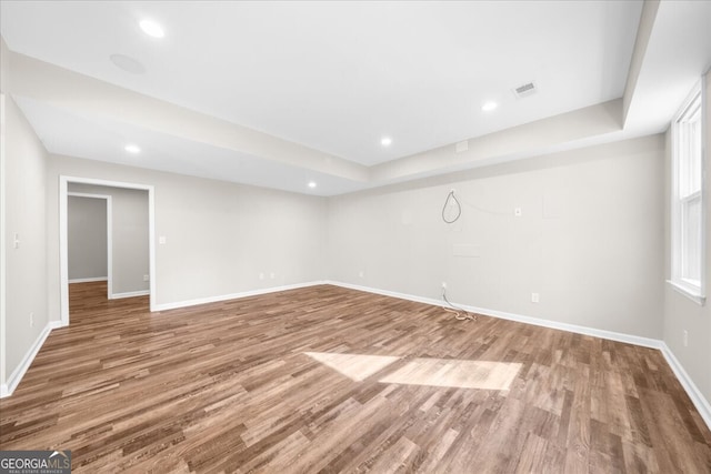 unfurnished room featuring wood-type flooring and a raised ceiling