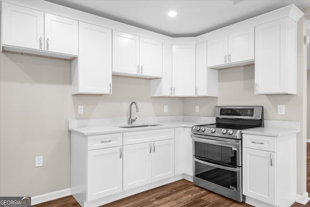 kitchen featuring stainless steel electric range oven, sink, white cabinets, and dark hardwood / wood-style floors