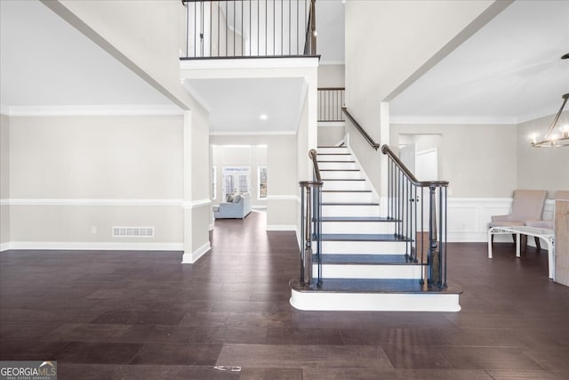 entryway featuring crown molding, dark hardwood / wood-style floors, and an inviting chandelier