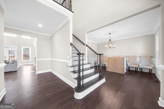 stairway featuring hardwood / wood-style floors, ornamental molding, and an inviting chandelier