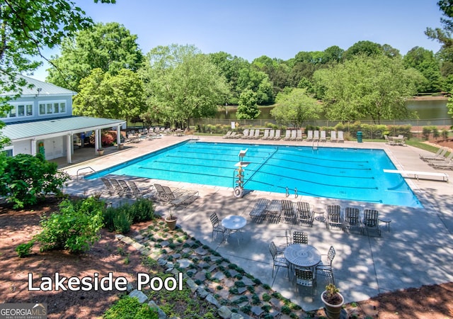 view of pool with a patio area, a diving board, and a water view