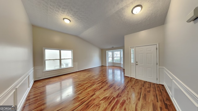 foyer entrance featuring wood-type flooring, a textured ceiling, and vaulted ceiling