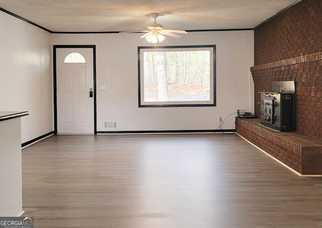 unfurnished living room featuring ceiling fan, wood-type flooring, and a textured ceiling