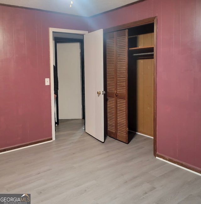 unfurnished bedroom with a textured ceiling, light wood-type flooring, and a closet