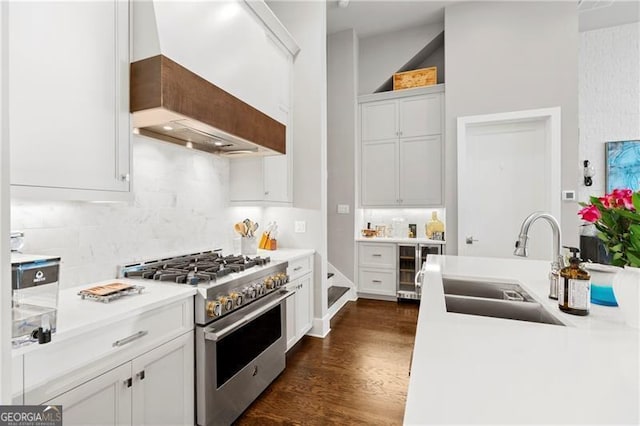 kitchen featuring backsplash, dark wood-type flooring, sink, high end stove, and white cabinetry