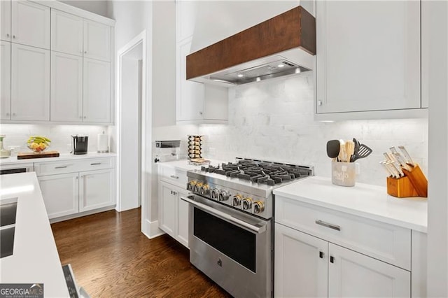 kitchen with high end stove, backsplash, white cabinets, and custom exhaust hood