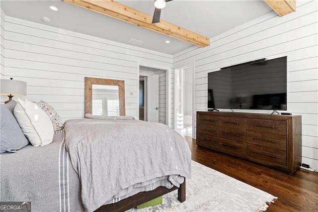 bedroom featuring beam ceiling, ceiling fan, dark hardwood / wood-style flooring, and wooden walls