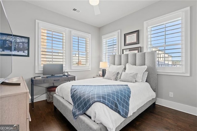 bedroom featuring multiple windows, dark hardwood / wood-style floors, and ceiling fan