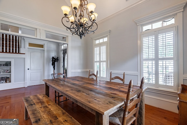 dining space featuring dark hardwood / wood-style flooring, crown molding, and an inviting chandelier