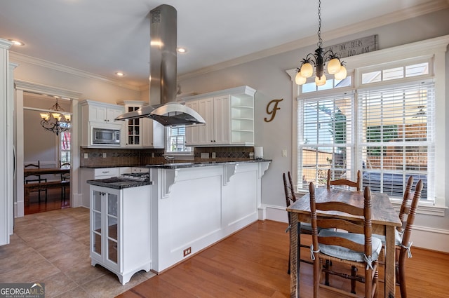 kitchen featuring a chandelier, pendant lighting, white cabinetry, and stainless steel microwave