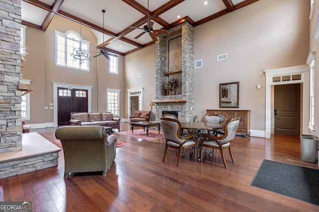 living room featuring ceiling fan, coffered ceiling, a stone fireplace, beamed ceiling, and dark hardwood / wood-style floors