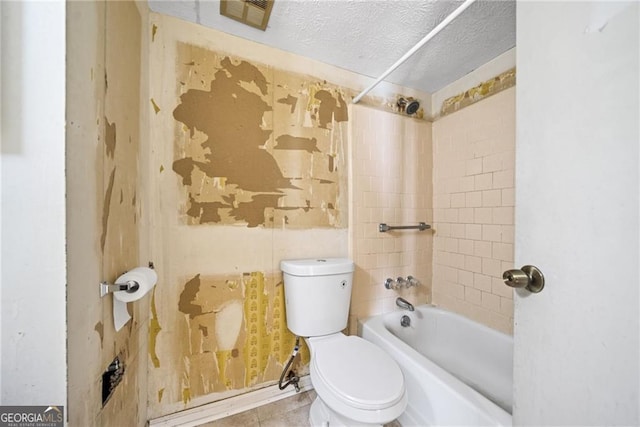 bathroom with toilet, a textured ceiling, and tiled shower / bath