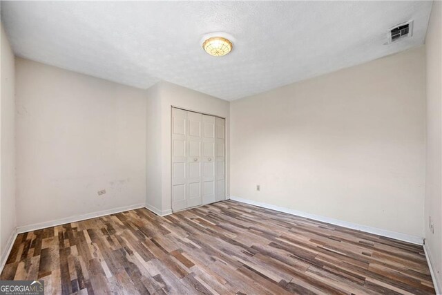 unfurnished bedroom featuring wood-type flooring, a textured ceiling, and a closet