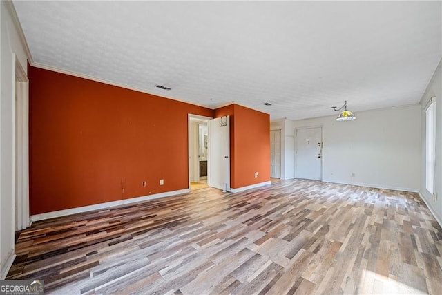 unfurnished room featuring hardwood / wood-style floors, ornamental molding, and a textured ceiling