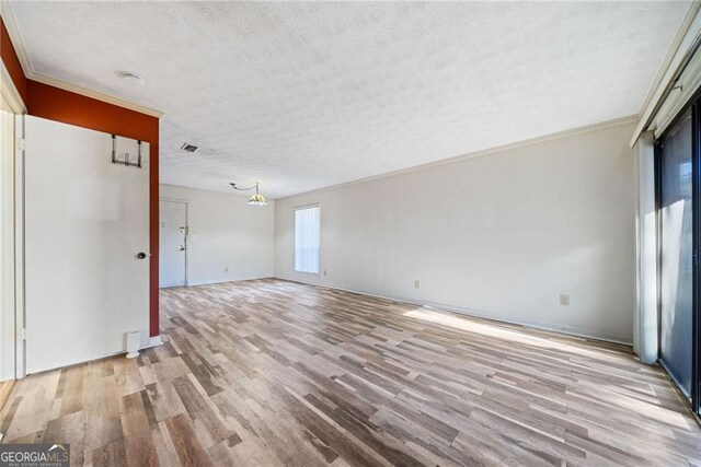 unfurnished room with ornamental molding, a textured ceiling, and light wood-type flooring