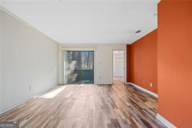 unfurnished room with a textured ceiling, light wood-type flooring, and ornamental molding