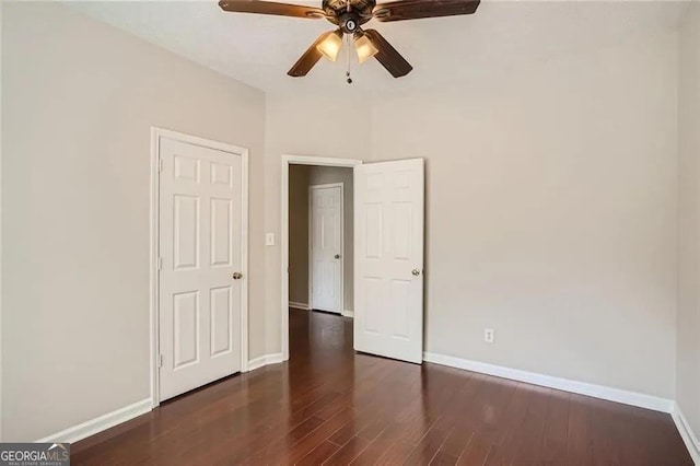 unfurnished bedroom with ceiling fan and dark wood-type flooring