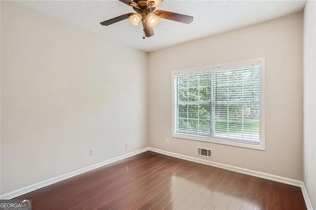 unfurnished room with ceiling fan and dark wood-type flooring