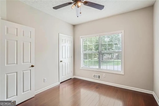 unfurnished room featuring a textured ceiling, ceiling fan, and dark hardwood / wood-style floors