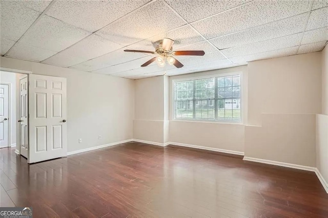 empty room featuring a paneled ceiling, dark hardwood / wood-style floors, and ceiling fan