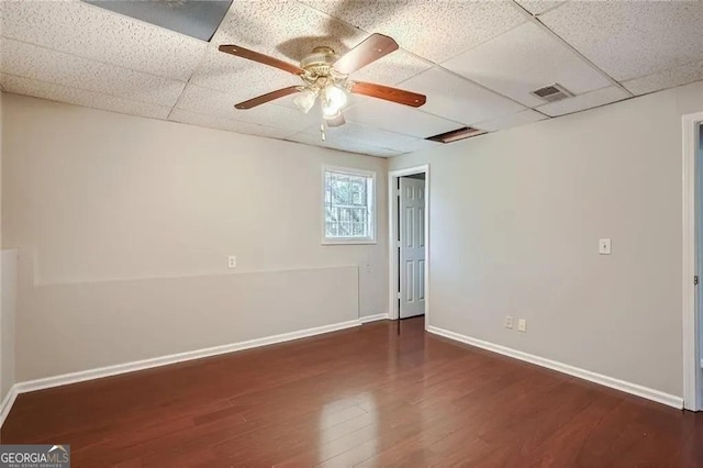 empty room featuring a paneled ceiling, ceiling fan, and dark hardwood / wood-style flooring