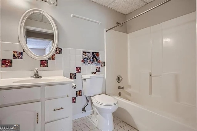 full bathroom with tile patterned flooring, toilet, shower / tub combination, vanity, and tile walls