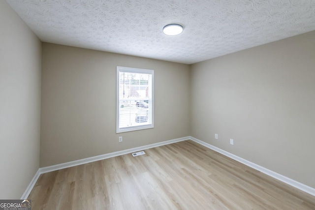 spare room with light hardwood / wood-style floors and a textured ceiling