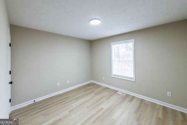 empty room with a textured ceiling and light wood-type flooring