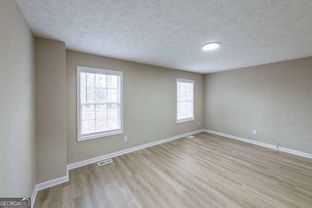 unfurnished room with light hardwood / wood-style floors and a textured ceiling