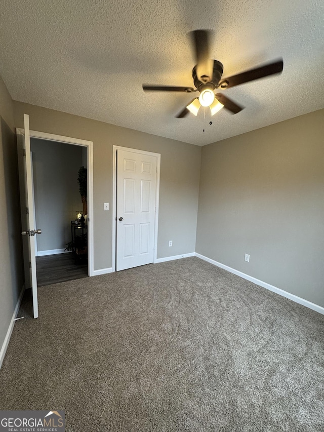 unfurnished bedroom with a textured ceiling, dark carpet, and ceiling fan