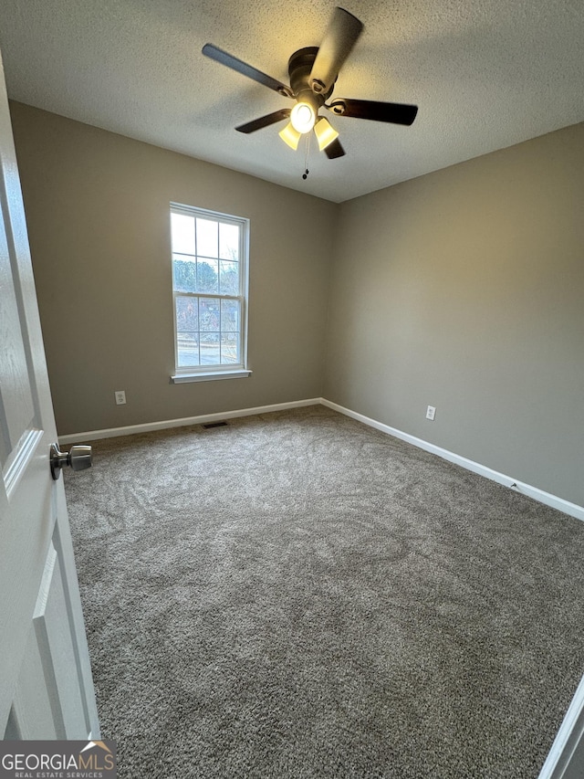 carpeted empty room with ceiling fan and a textured ceiling