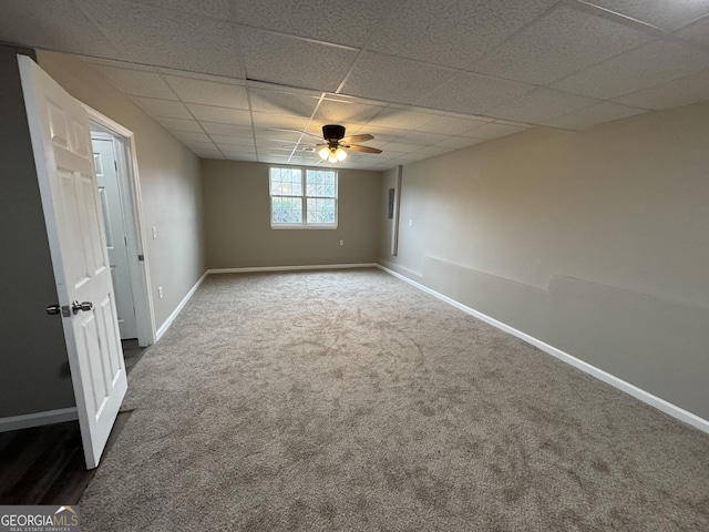 empty room featuring a paneled ceiling, ceiling fan, and dark colored carpet