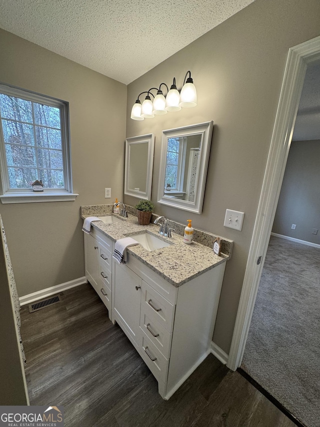 bathroom with hardwood / wood-style floors, vanity, and a textured ceiling