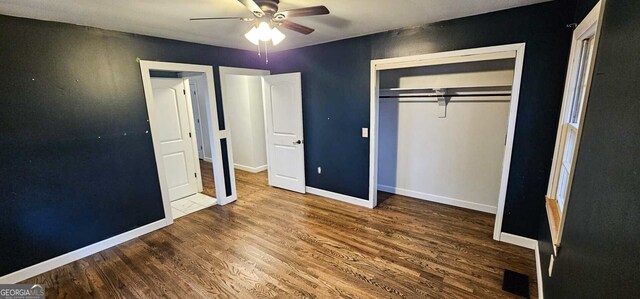 unfurnished bedroom with ceiling fan, dark hardwood / wood-style floors, and a closet