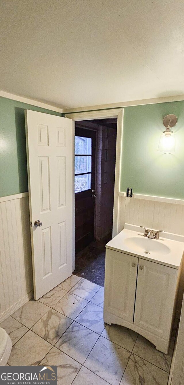 bathroom with toilet, vanity, and ornamental molding