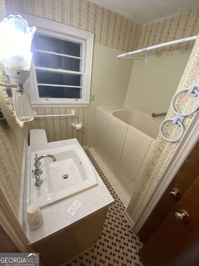 bathroom with tile patterned flooring, sink, and a bath