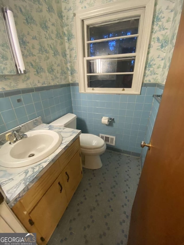 bathroom featuring vanity, tile walls, tile patterned floors, and toilet