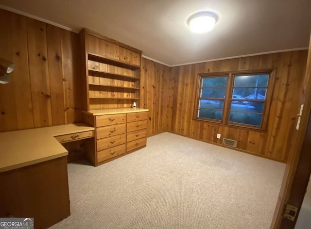 carpeted home office with crown molding and wood walls