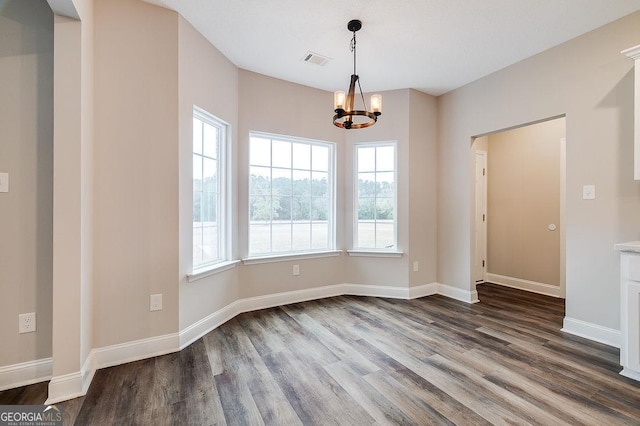 unfurnished dining area with hardwood / wood-style floors and a notable chandelier