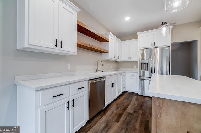 kitchen featuring appliances with stainless steel finishes, decorative light fixtures, white cabinetry, and sink